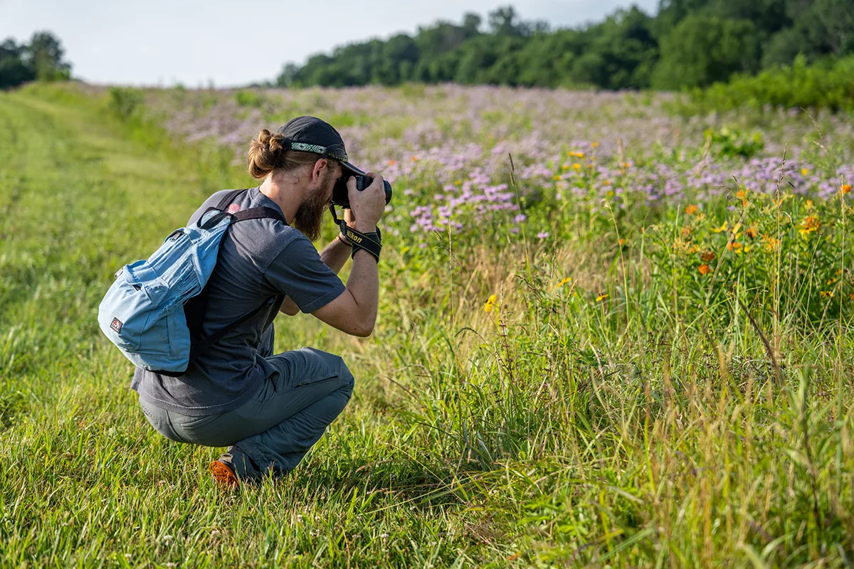 a man crouches to take a photo of a meadow