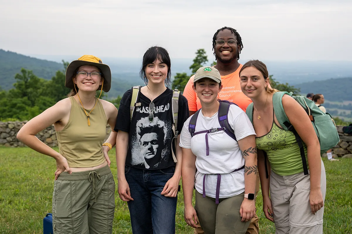 four young woman and a man smile at a mountain overlook