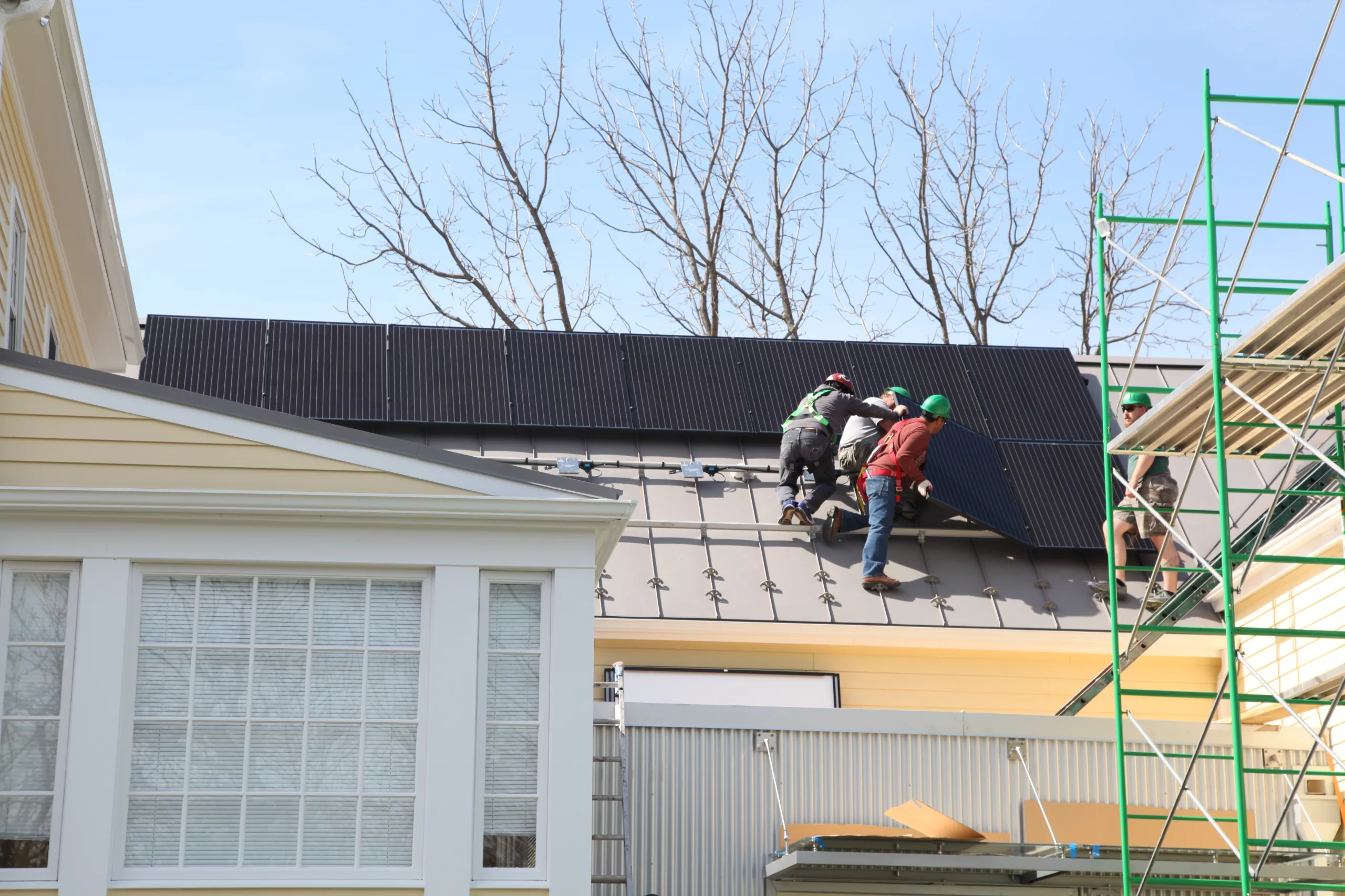 four men install solar panels on a roof