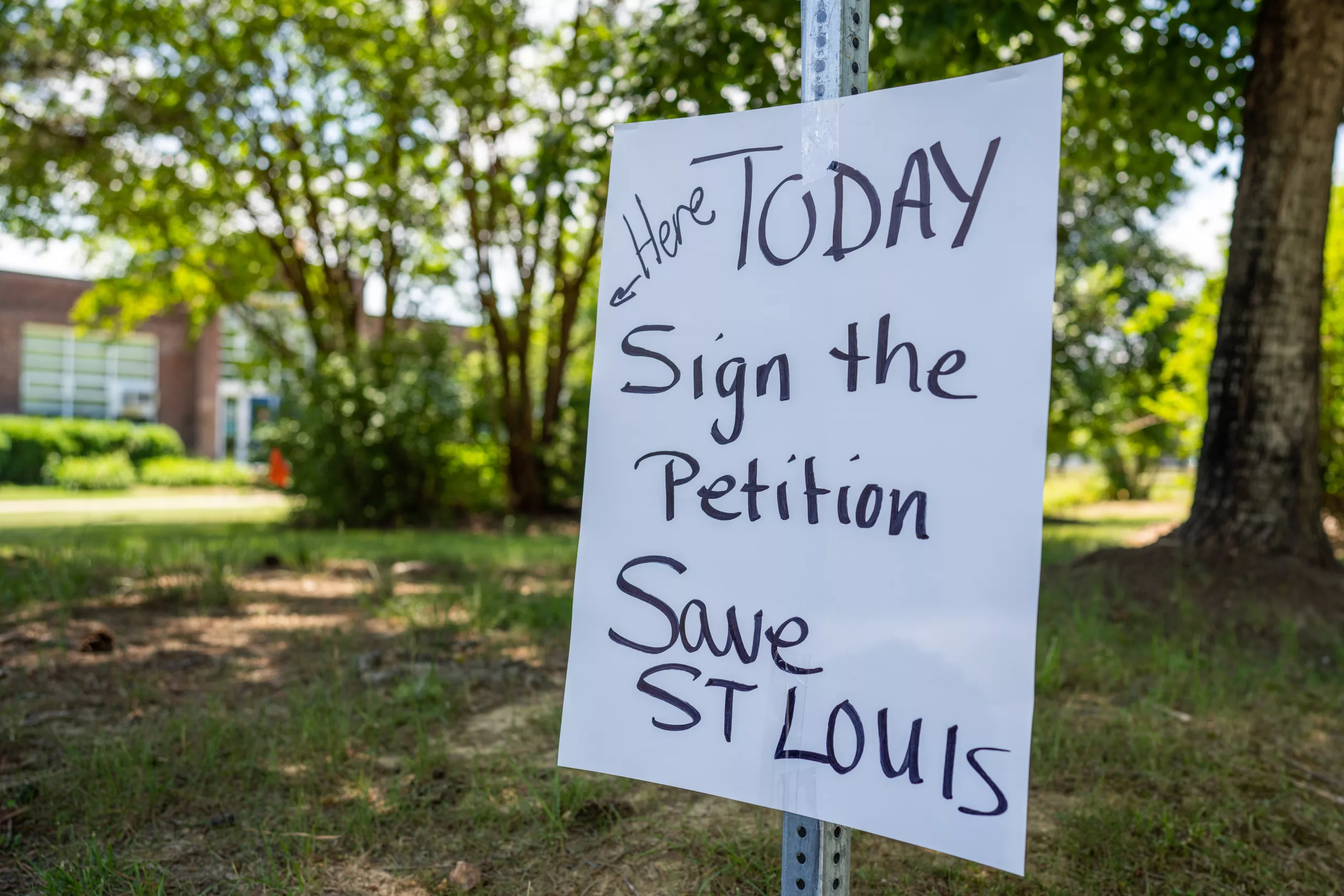 a handwritten sign that says "today, sign the petition, save St. Louis"
