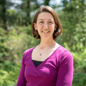Headshot of a woman with short brown hair wearing a magenta top.