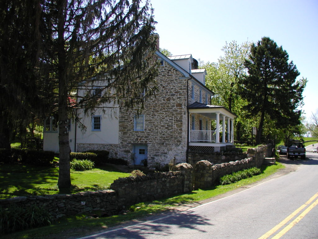 An old stone building with a stone wall next to a road.