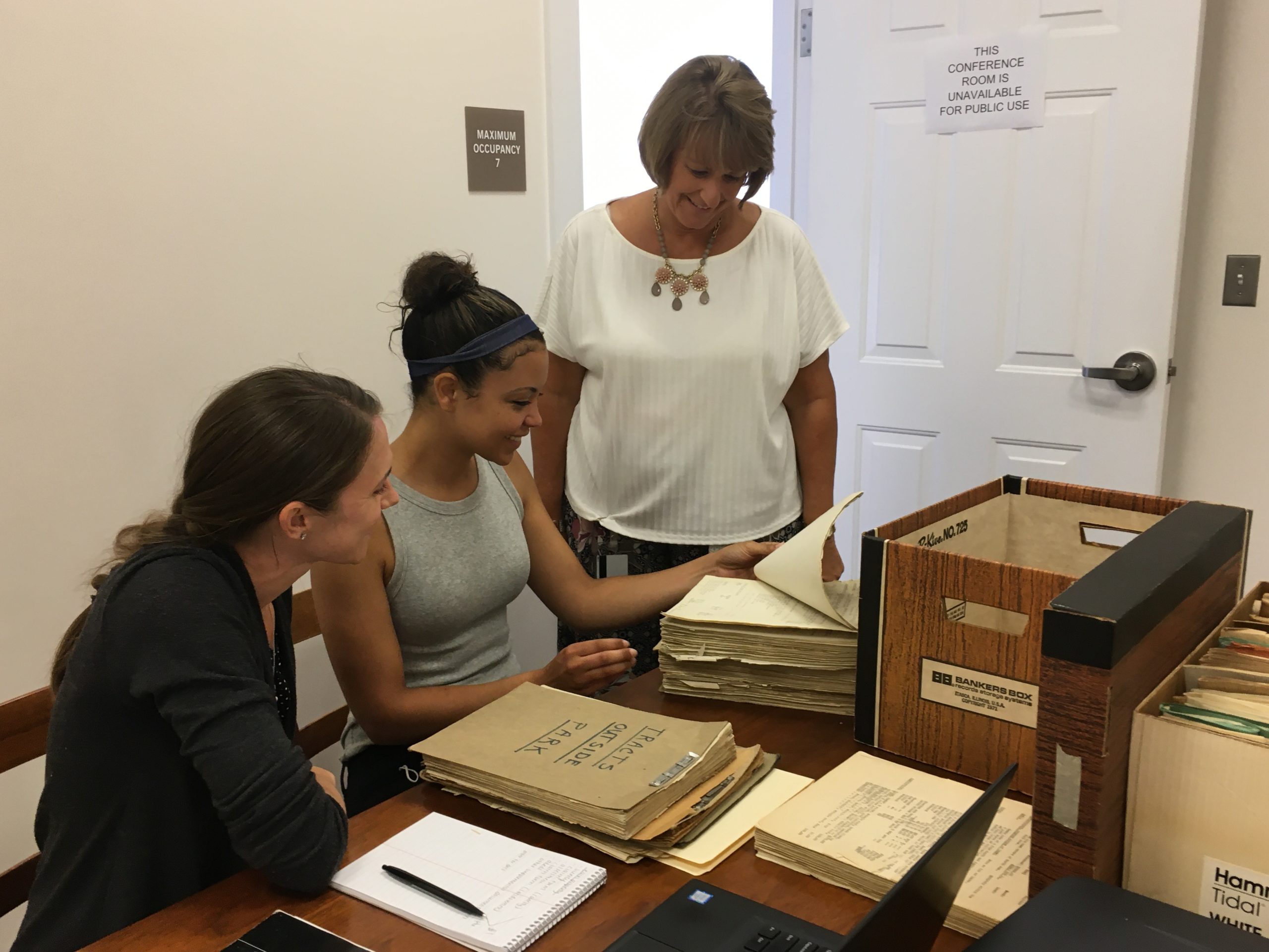 three women look over boxes of historic records