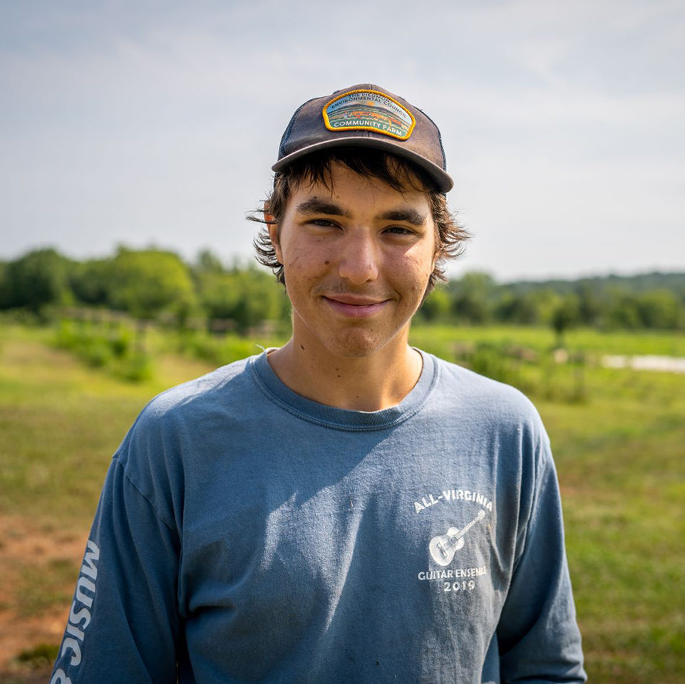 a young white man wearing a hat on a farm