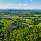 aerial image of green farmland and forest with the Blue Ridge Mountains in the distance