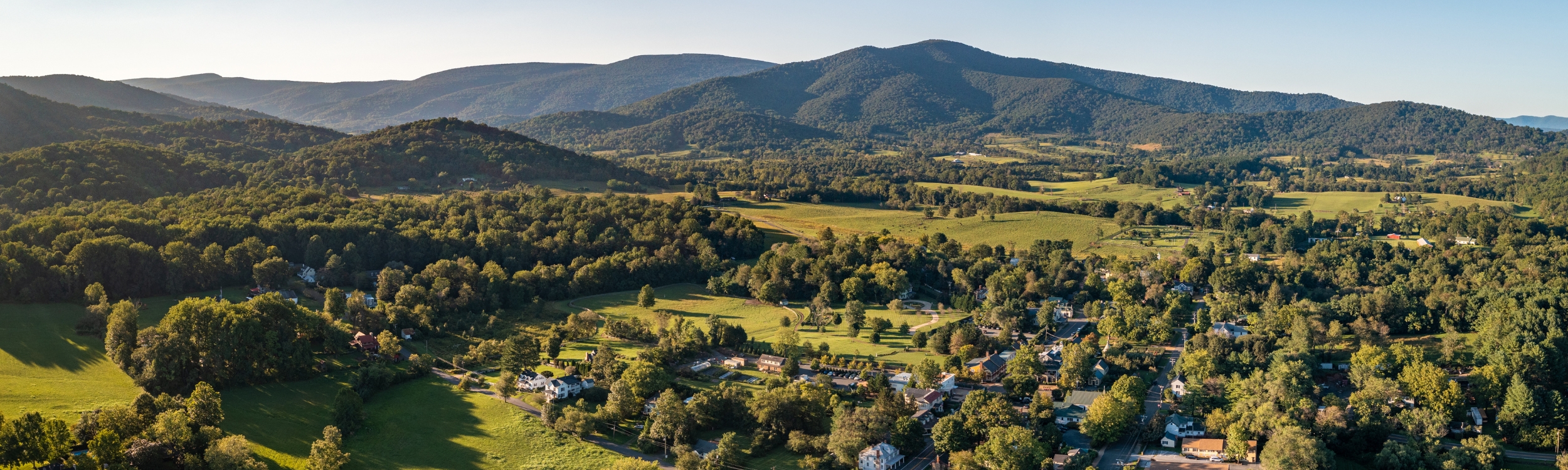 aerial view of green mountains and a small town during late afternoon light