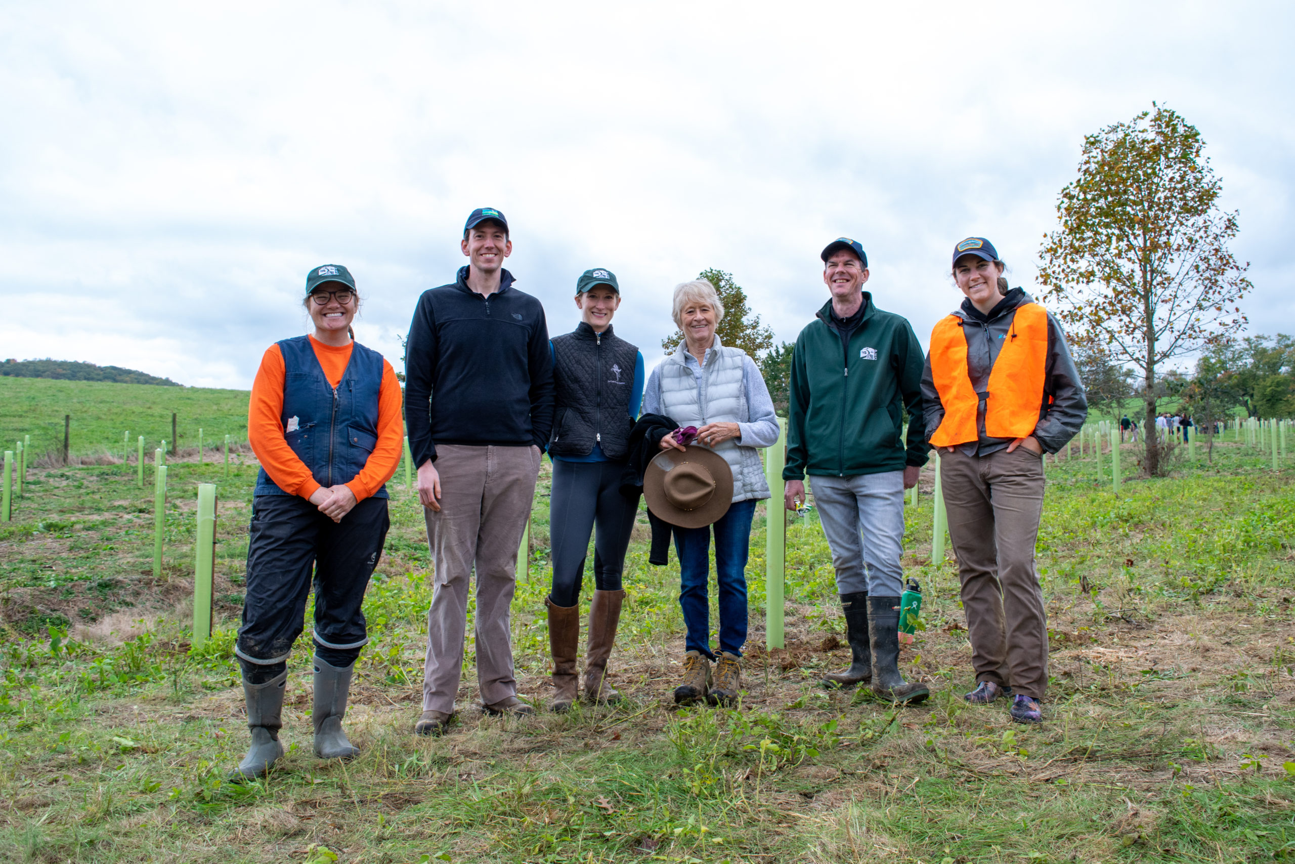 a group stands at the site of a tree planting