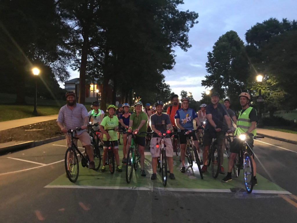 a group of people with their bikes, with lights and reflective gear at night
