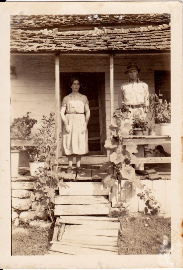 sepia image of a man and woman standing on a front porch