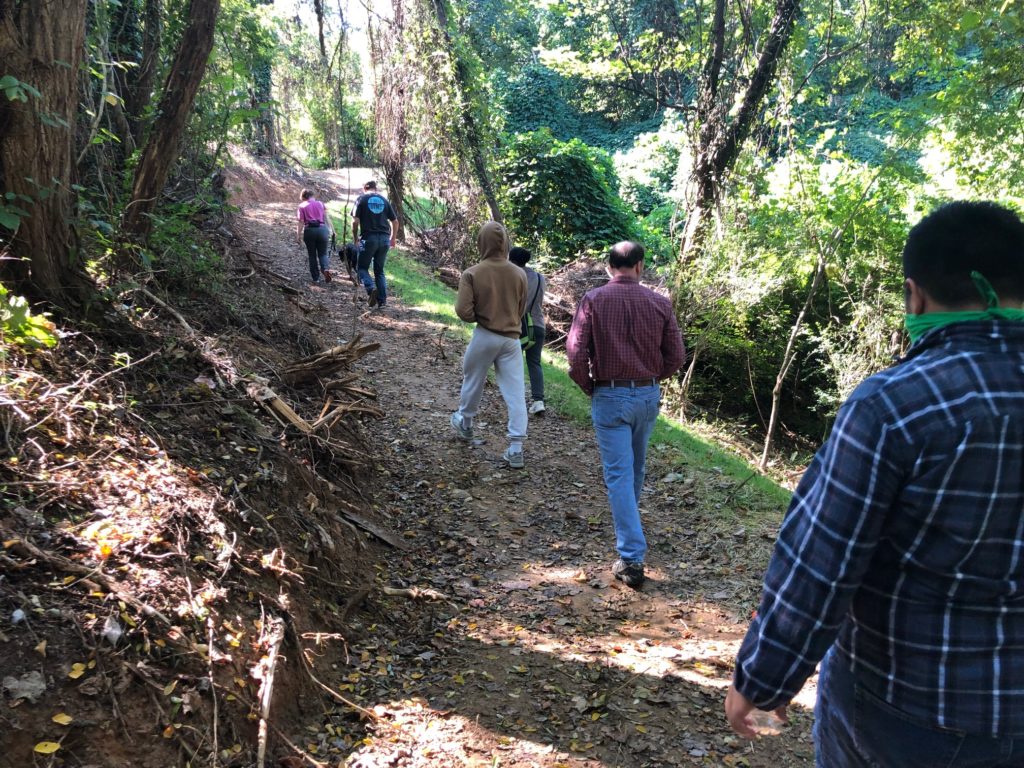 a group of neighbors walk up a sloped, forested trail