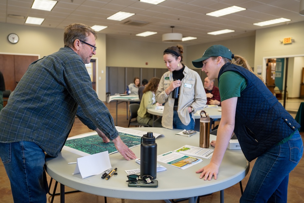 People leaning over a table looking at a map.