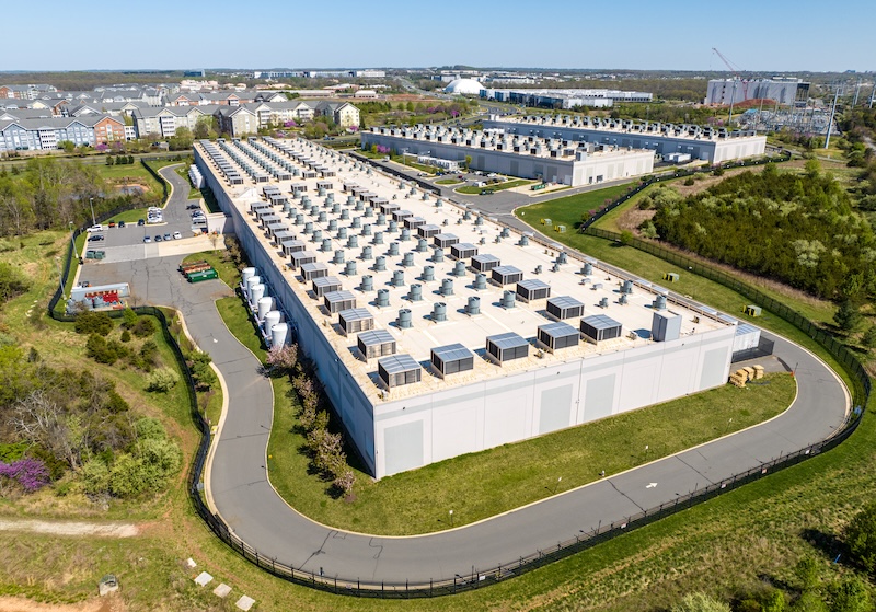 Three data centers look like large, windowless warehouses next to apartments and townhomes.