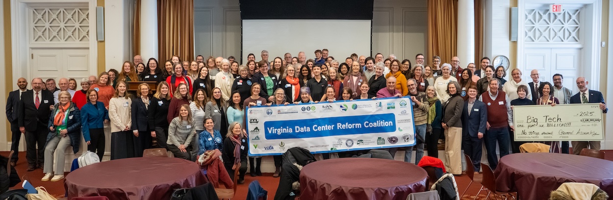 Large group photo at event. People are holding a sign that says "Virginia Data Center Reform Coalition" and a large decorative check made out to "Big Tech" for "one point nine BILLION!"