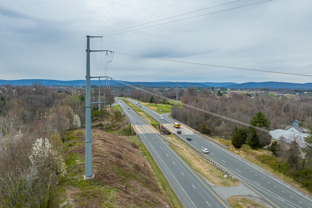 a transmission line looms over traffic