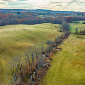 aerial view of a meandering stream through two fields in a rural landscape during autumn