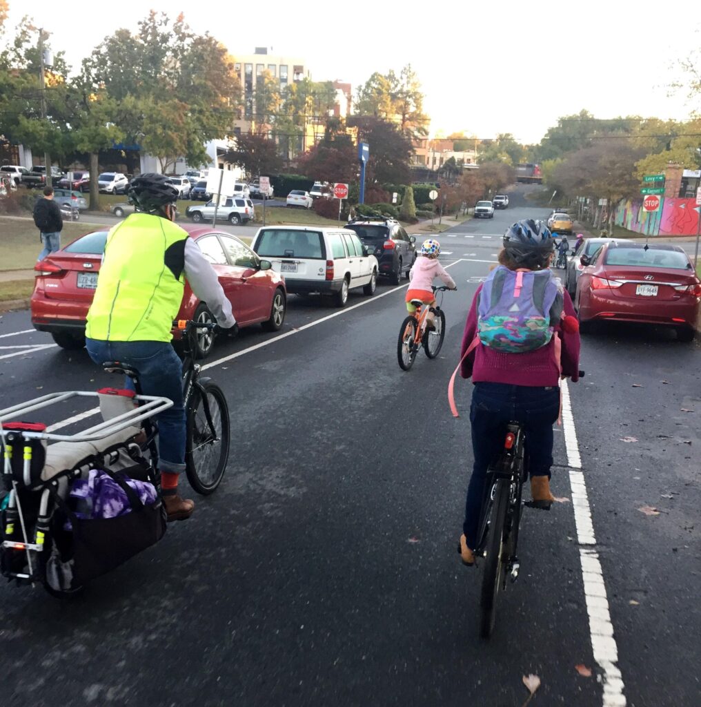 three people in yellow and pink bike on road