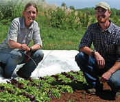 A man and woman crouch in a farm bed.