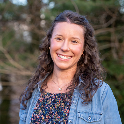 headshot of a woman with curly hair outdoors.