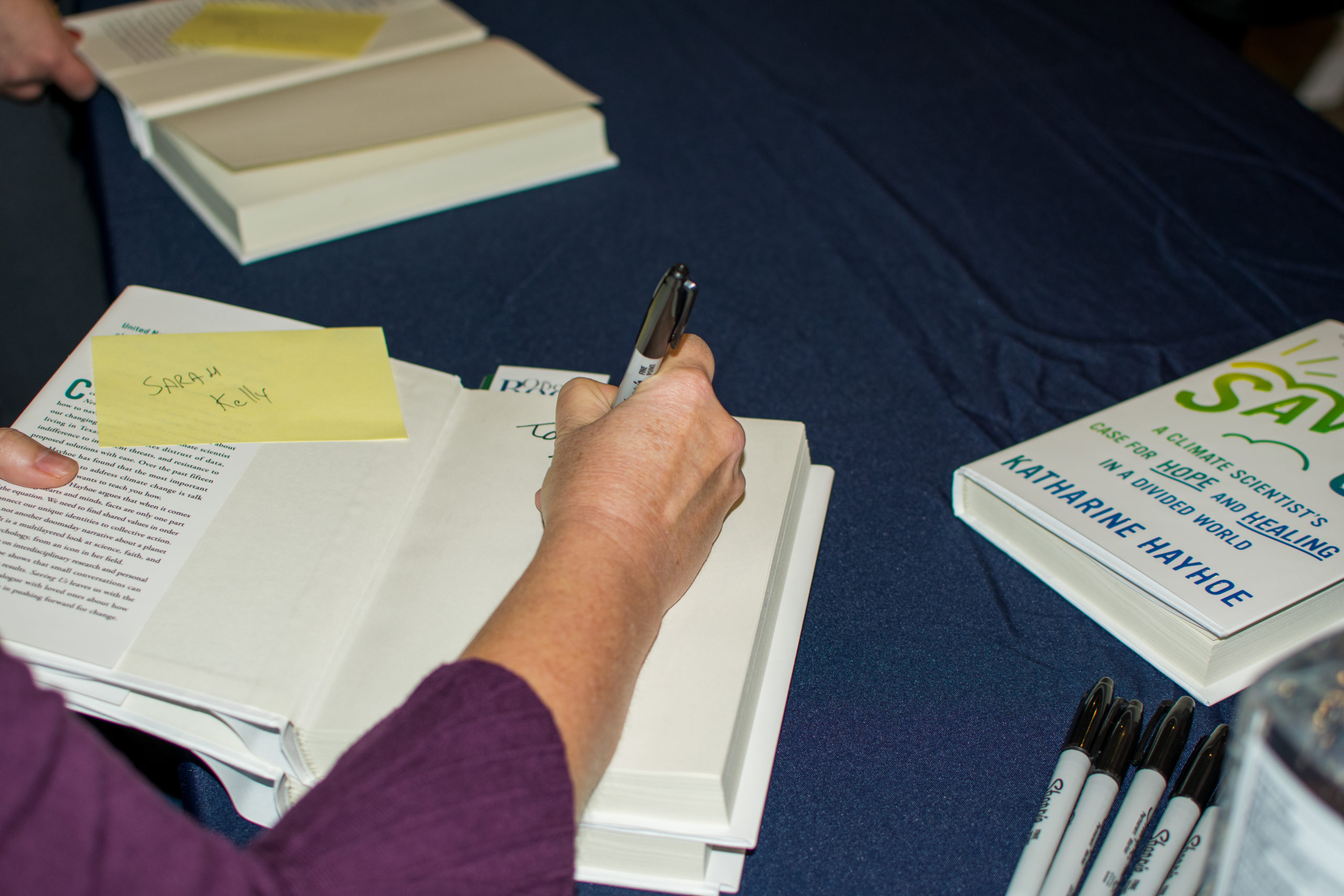close-up of Katharine Hayhoe signing a book