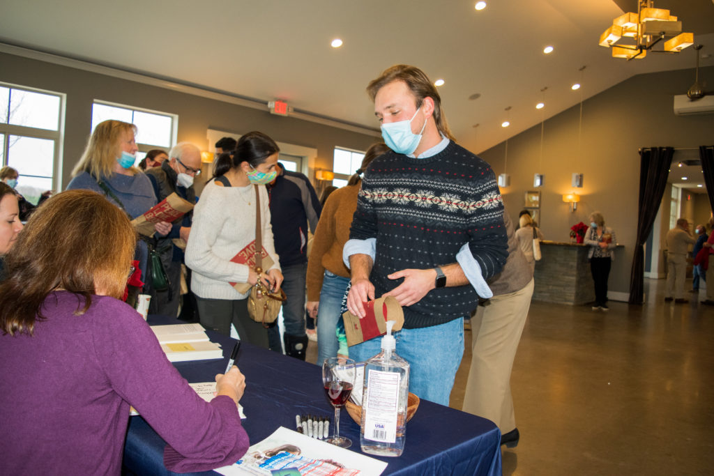 a young man speaks to Katharine Hayhoe as she signs his copy of the book