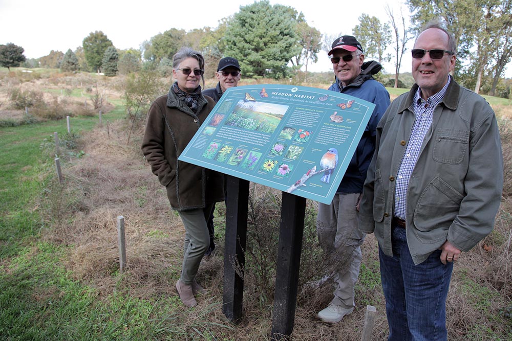 A group of people stand near a sign.