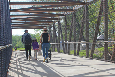 People walk across a metal bridge.