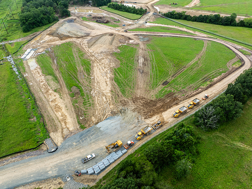 Aerial view of a construction site with dirt paths and dump trucks along the path.