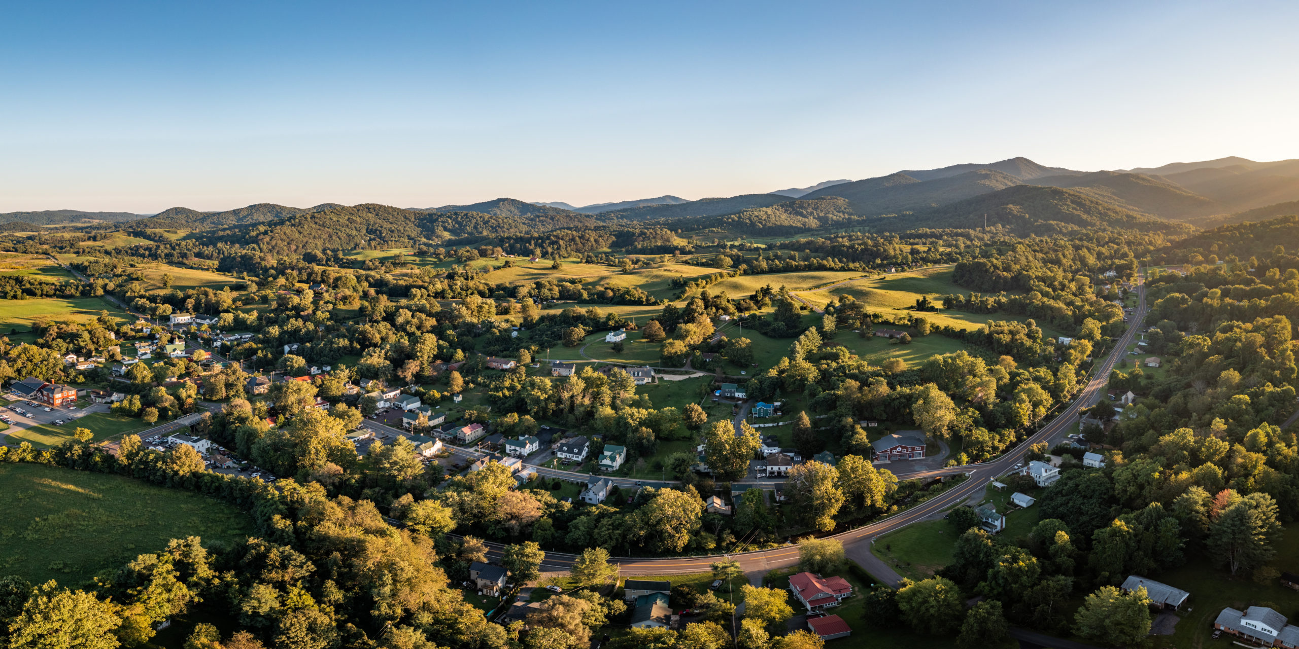 landscape aerial image of green mountains and fields dotted with forests and a town