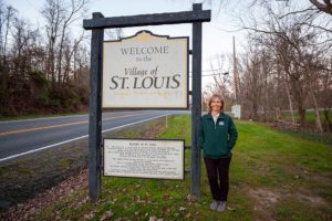 Gem Bingol stands near Village of St Louis sign