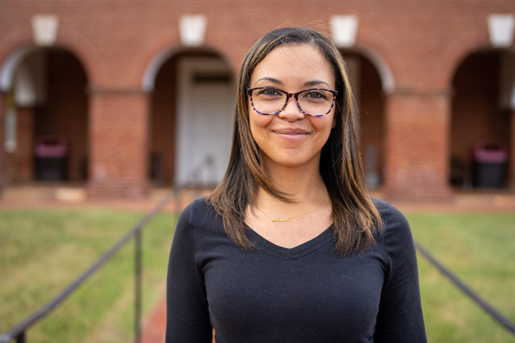 a Black woman with a brick building behind her