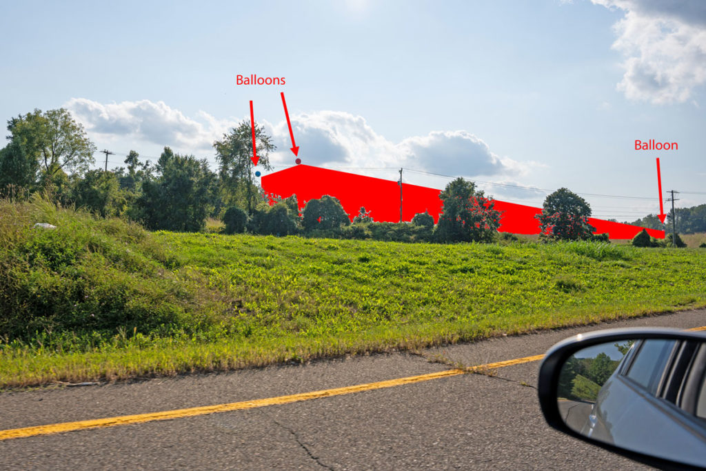 rendering of red data center on hillside of grass and trees